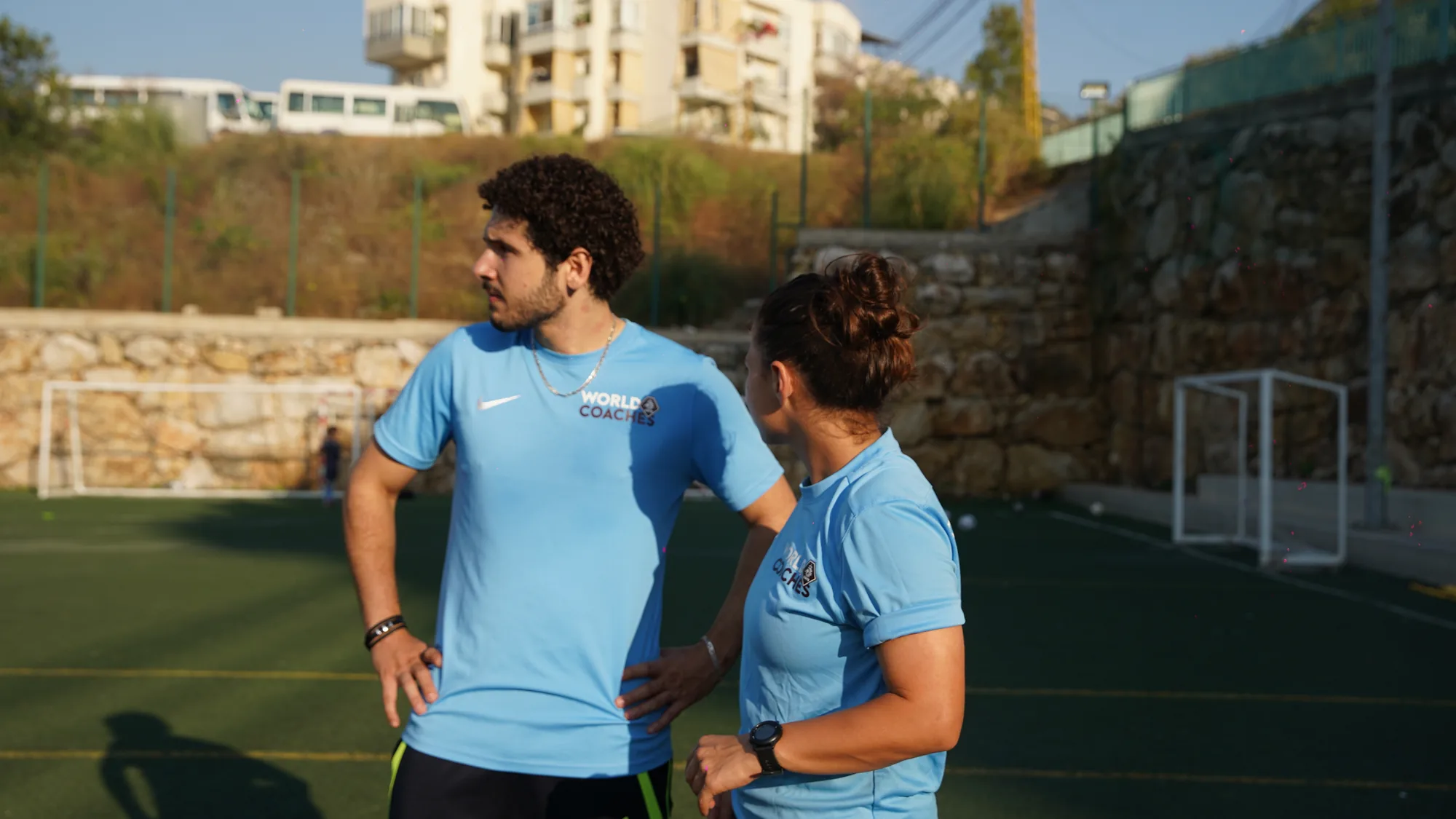 Two coaches watching a drill from the touchline